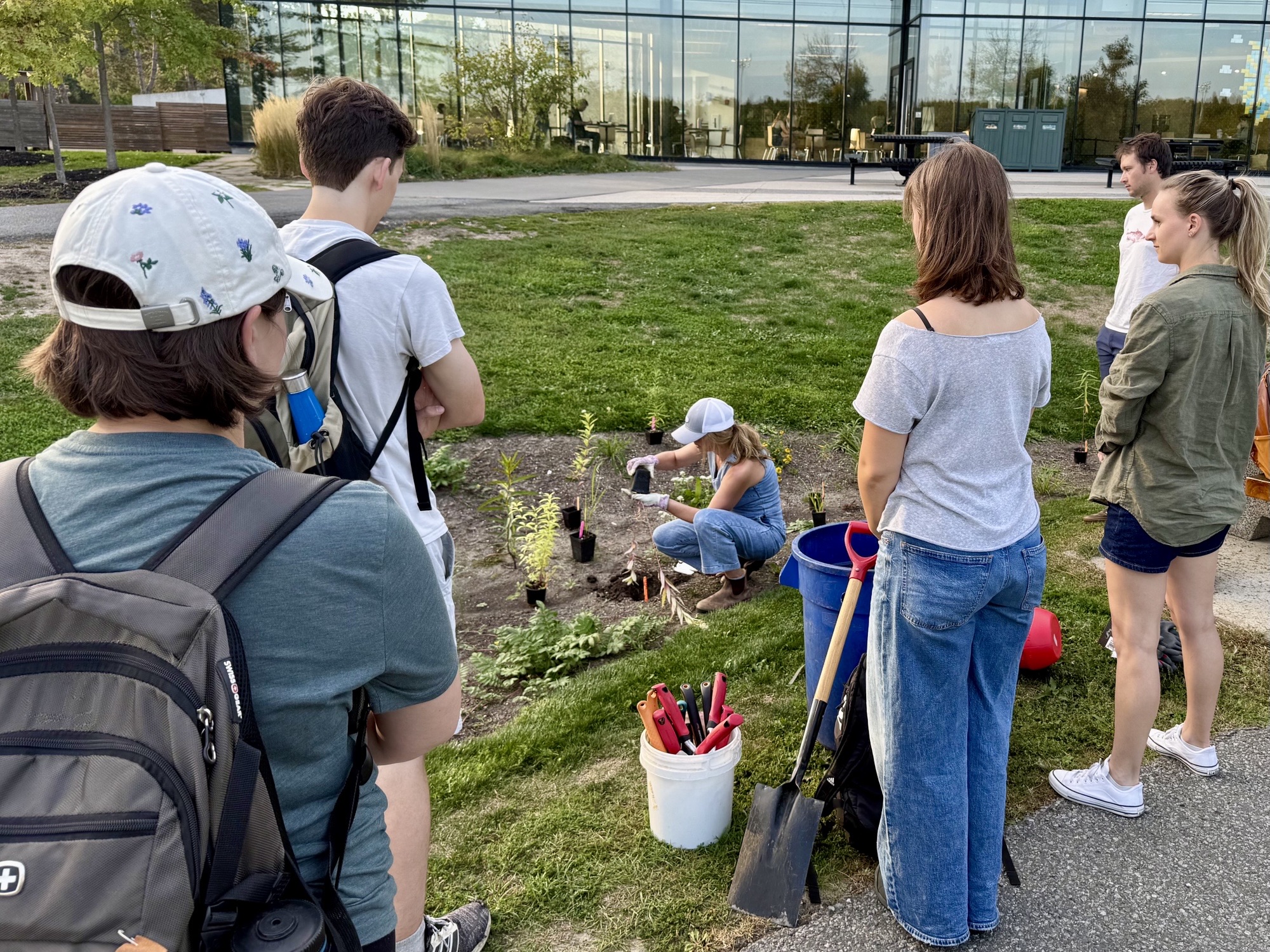 Go Wild Grant Recipient: Trent University Students standing around a native plant garden while one student demonstrates how to plant.